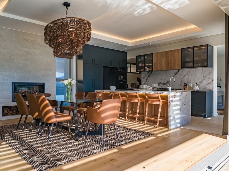 Modern open-plan living and dining area featuring a stone-clad fireplace, high-end kitchen with marble island, and premium hardwood flooring throughout.