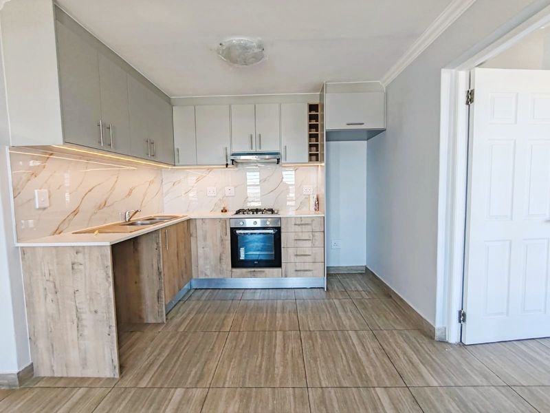 Modern kitchen featuring two-tone cabinetry, marble-look splashback, built-in oven, gas hob, and tiled flooring in a clean, contemporary layout.