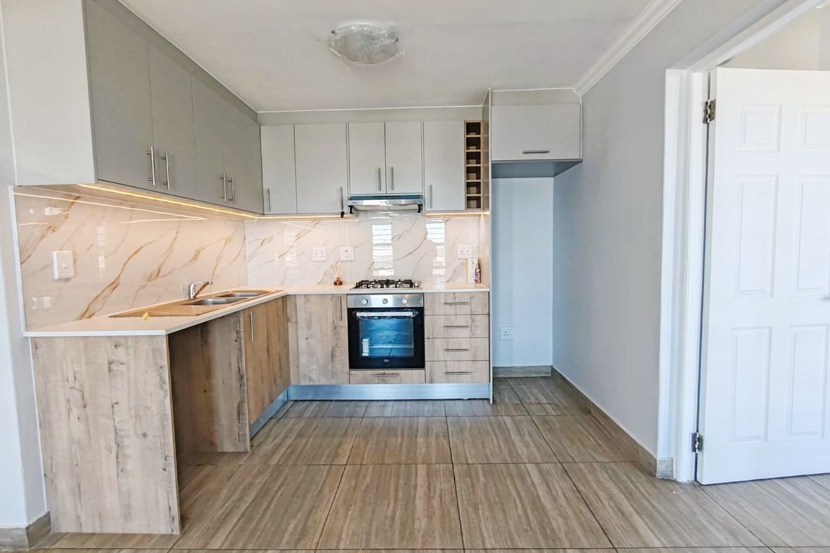 Modern kitchen featuring two-tone cabinetry, marble-look splashback, built-in oven, gas hob, and tiled flooring in a clean, contemporary layout.