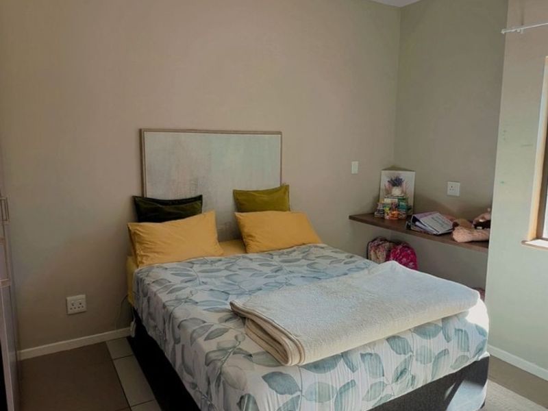 A well-maintained bedroom featuring neutral wall tones, tiled flooring, recessed lighting, and a convenient built-in desk area.
