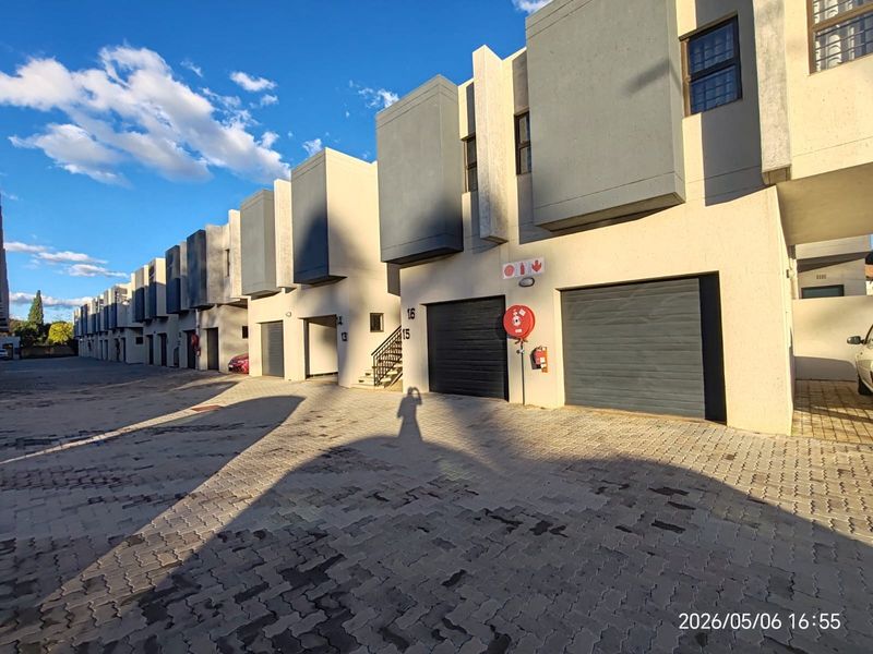 Modern apartment complex exterior featuring paved driveway access, multiple sectional garage doors, and external staircases for unit access.
