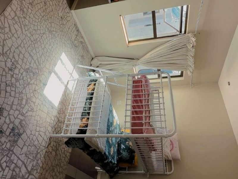 A bedroom featuring built-in shelving and a window with curtain rails, providing natural light and functional storage space.