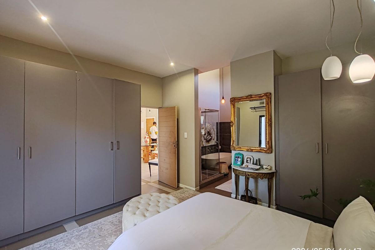Spacious bedroom featuring extensive built-in cupboards, recessed lighting, and direct access to an en-suite bathroom with a modern layout.