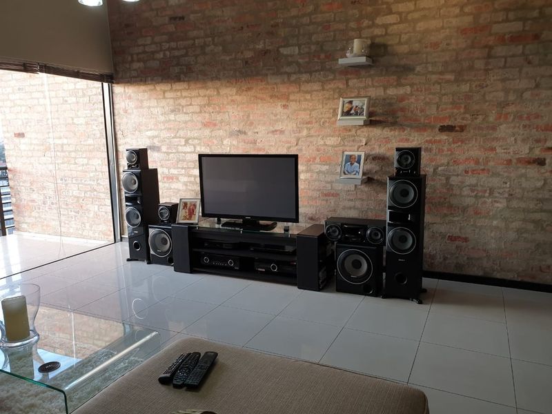 A living room featuring an exposed brick feature wall, large format floor tiles, and a sliding glass door leading to an outdoor area.