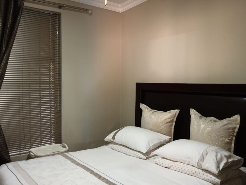 A well-maintained bedroom featuring a ceiling fan, crown molding, and venetian blinds, providing a comfortable and functional living space.