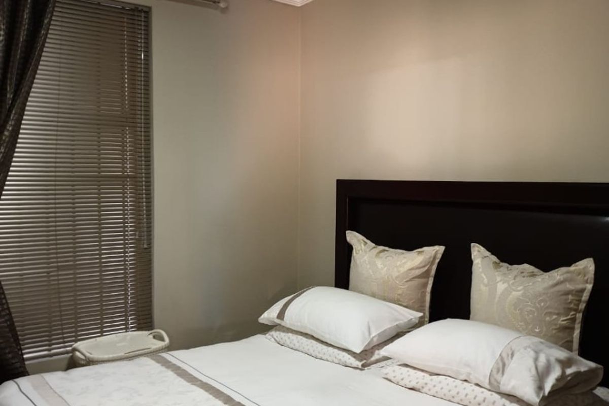 A well-maintained bedroom featuring a ceiling fan, crown molding, and venetian blinds, providing a comfortable and functional living space.