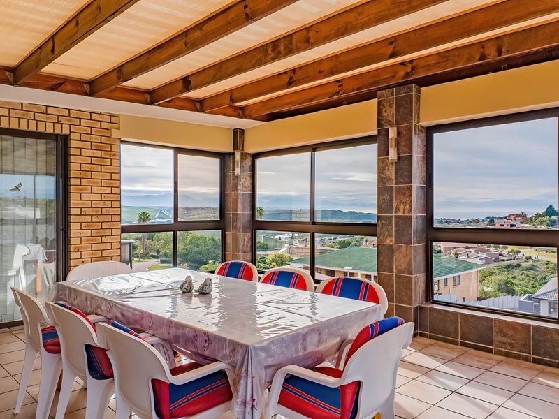 Enclosed patio area featuring exposed timber beams, tiled flooring, and large windows offering expansive views, suitable for an entertainment or dining space.