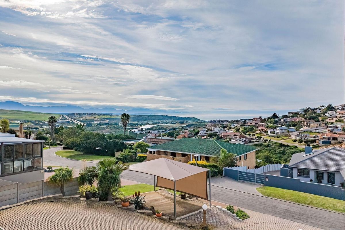 Elevated aerial view of the property exterior, showcasing the driveway, shade sail parking area, and surrounding neighbourhood landscape with distant mountain views.