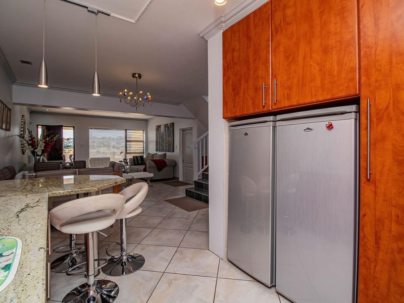Open plan living area featuring a kitchen with granite countertops and built-in cabinetry, flowing into a spacious lounge with tiled flooring.