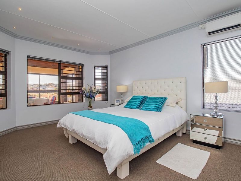 A well-maintained bedroom featuring carpeted flooring, recessed lighting, a split-system air conditioner, and large windows with venetian blinds.