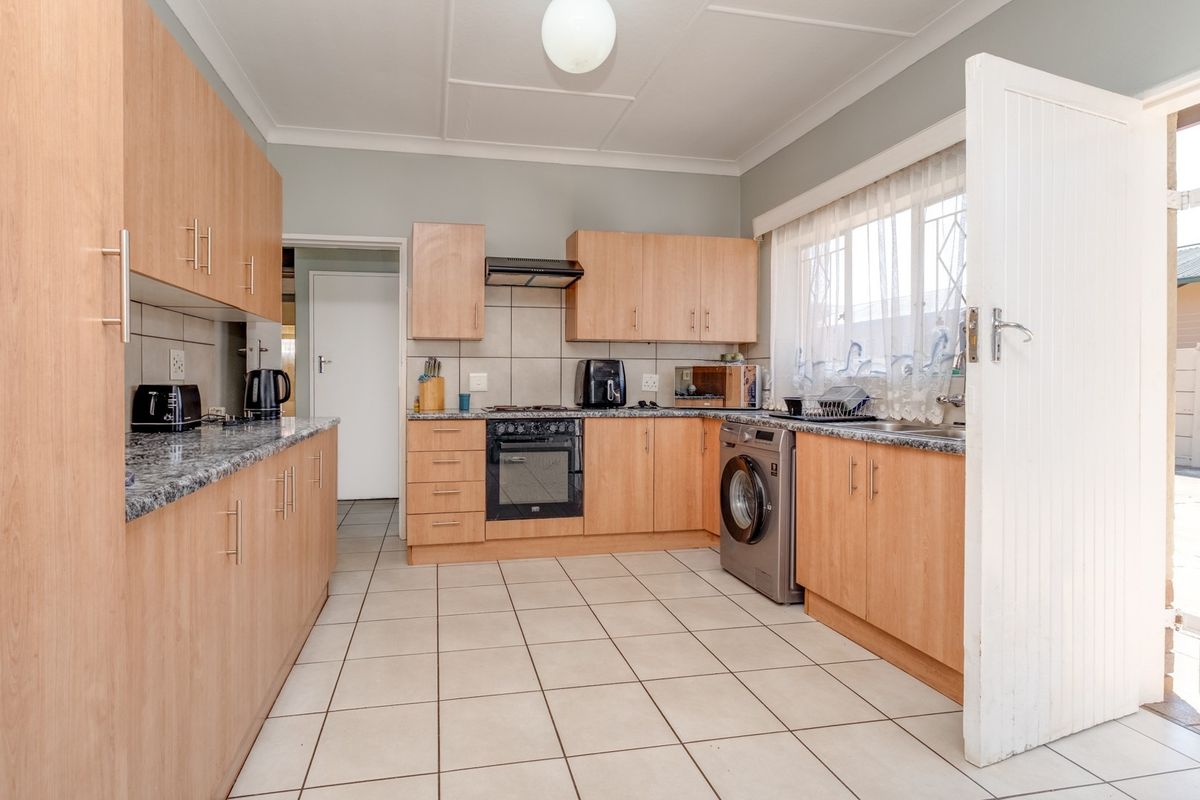 Functional kitchen featuring light wood-finish cabinetry, granite countertops, tiled flooring, and integrated appliances, offering a practical layout with ample storage space.