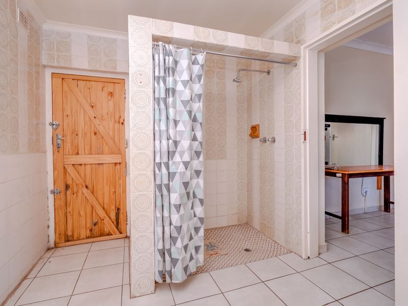 A functional bathroom featuring a walk-in shower with tiled surround and a rustic timber door, presenting an opportunity for modern renovation.