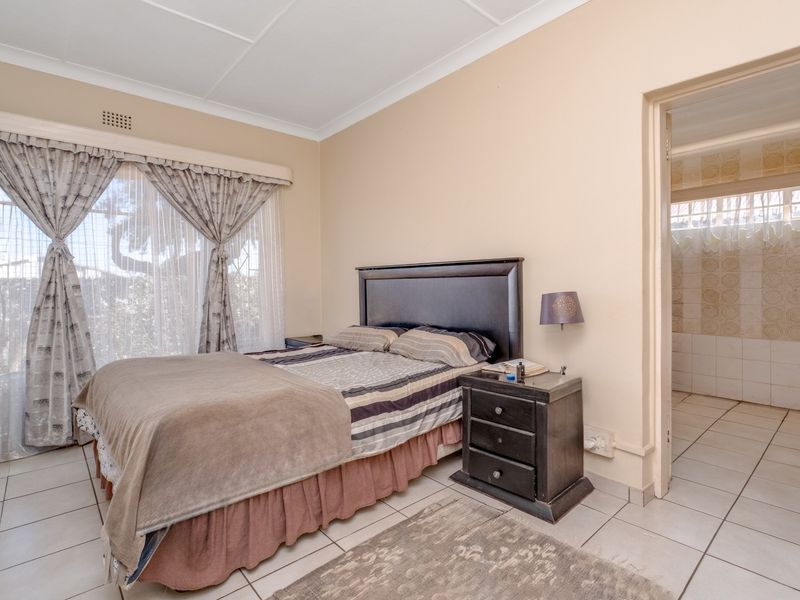 A bedroom featuring tiled flooring, coved ceilings, and direct access to an en-suite bathroom.