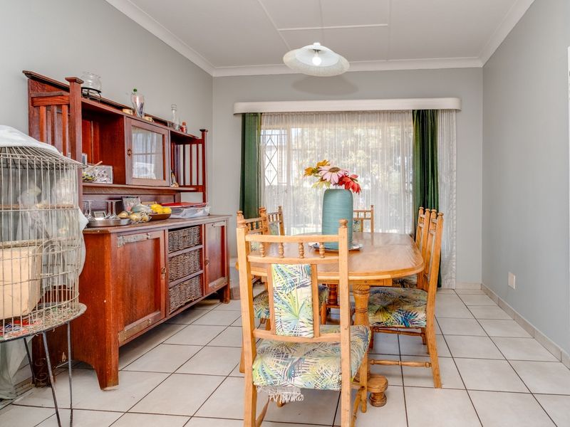 A well-lit dining room featuring neutral wall tones, tiled flooring, and a classic cove cornice finish, providing a functional space for family meals.
