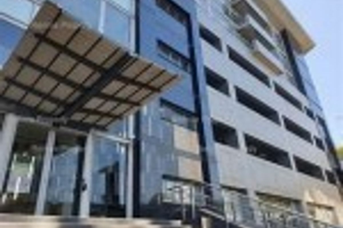 Modern commercial building facade featuring a glass curtain wall, prominent metal entrance canopy, and sleek cladding, showcasing a professional and contemporary architectural design.