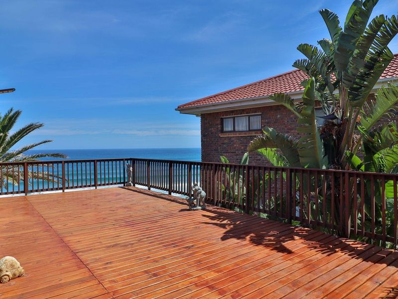 Spacious timber deck balcony featuring a wooden balustrade, offering expansive ocean views and direct access to the main residence.