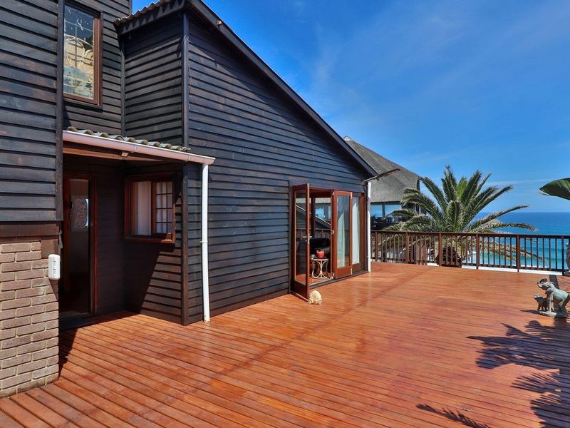 Spacious timber deck featuring a wooden balustrade, offering direct access to the home and scenic coastal views.