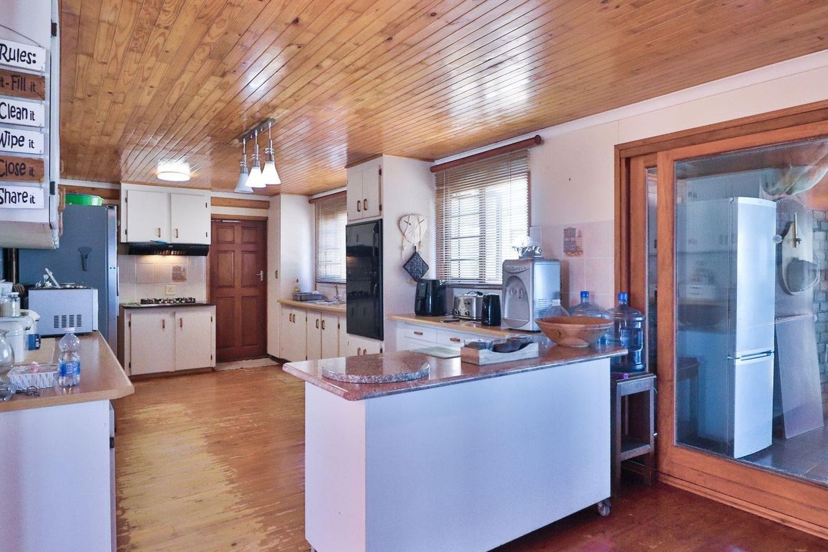 A spacious kitchen featuring timber ceilings, built-in cabinetry, and a central island, offering a functional layout with potential for modern updates.