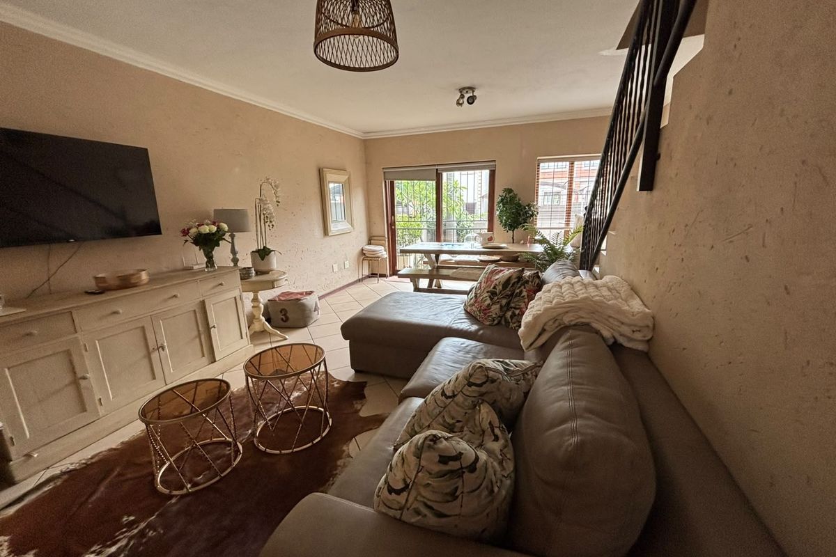 Open-plan living area featuring tiled flooring, a staircase with metal railing, and sliding glass doors leading to an outdoor space.