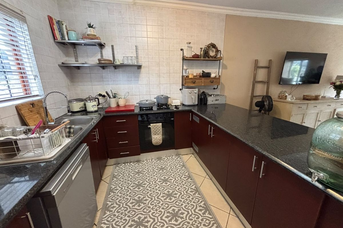 A functional kitchen featuring dark cabinetry, granite countertops, a built-in oven, and a tiled backsplash, offering a practical layout for daily meal preparation.