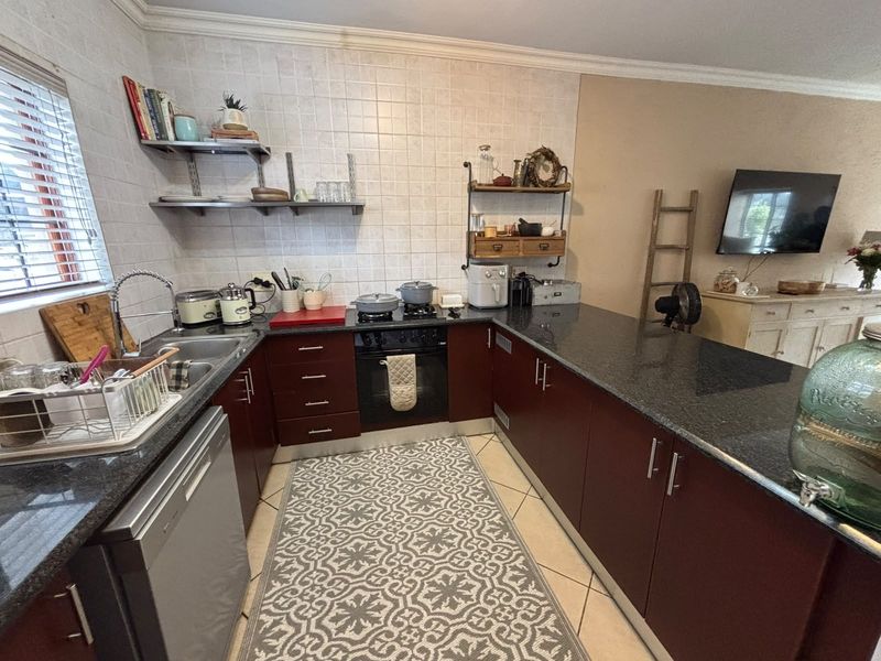 A functional kitchen featuring dark cabinetry, granite countertops, a built-in oven, and a tiled backsplash, offering a practical layout for daily meal preparation.