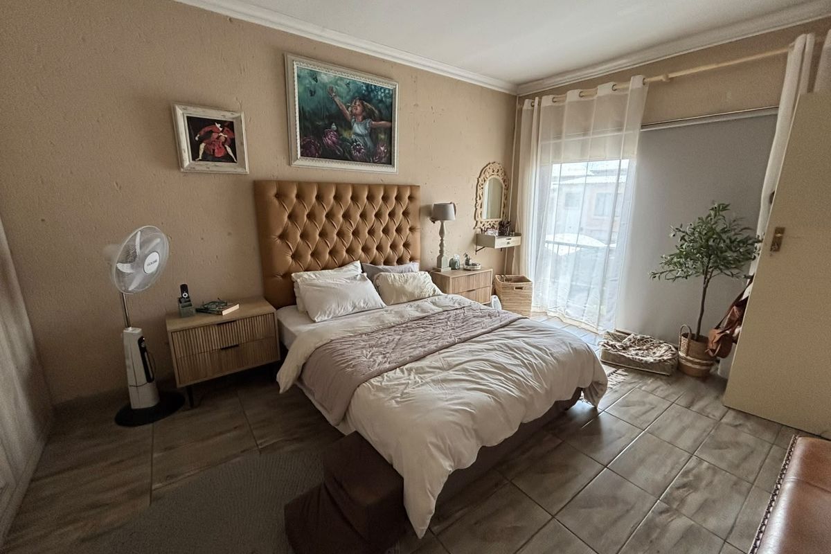 A well-lit bedroom featuring tiled flooring and a sliding glass door providing access to the exterior.