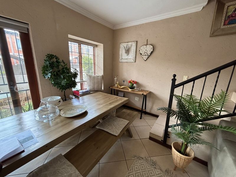 Dining area featuring tiled flooring, a staircase with metal railing, and natural light through a sliding glass door and window.
