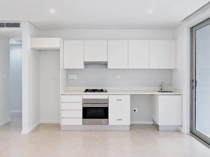 Modern, minimalist kitchen featuring white cabinetry, integrated stainless steel appliances, gas hob, and direct access to an outdoor balcony area.