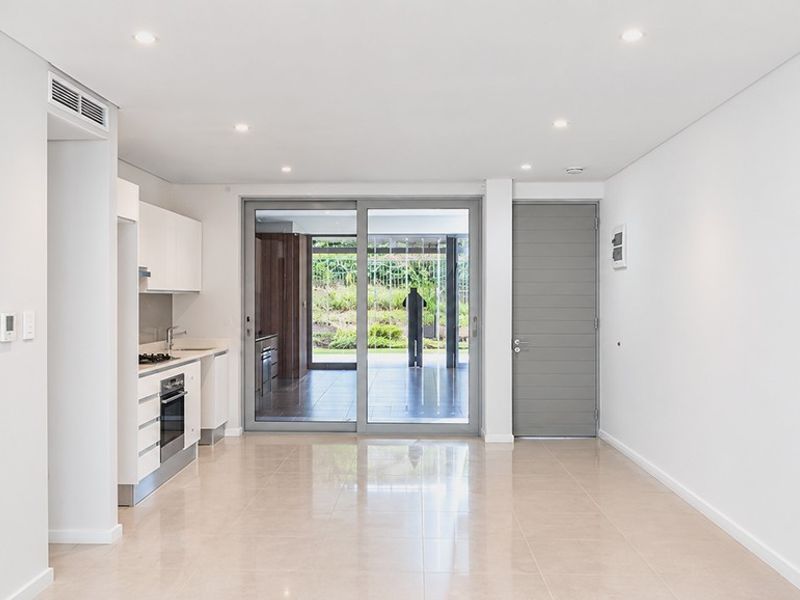 Modern open-plan living area featuring a sleek kitchen with built-in appliances, tiled flooring, and large sliding doors leading to an outdoor space.