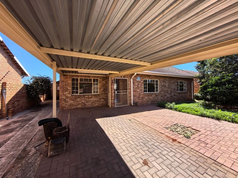 Front exterior view of the townhouse featuring a covered carport, facebrick facade, and paved driveway area.