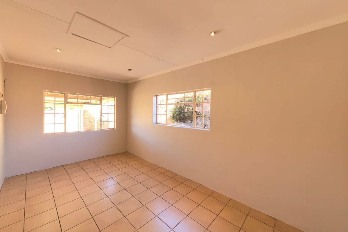 A bright, empty bedroom featuring neutral walls, tiled flooring, and steel-framed windows, offering a clean canvas for personalization.
