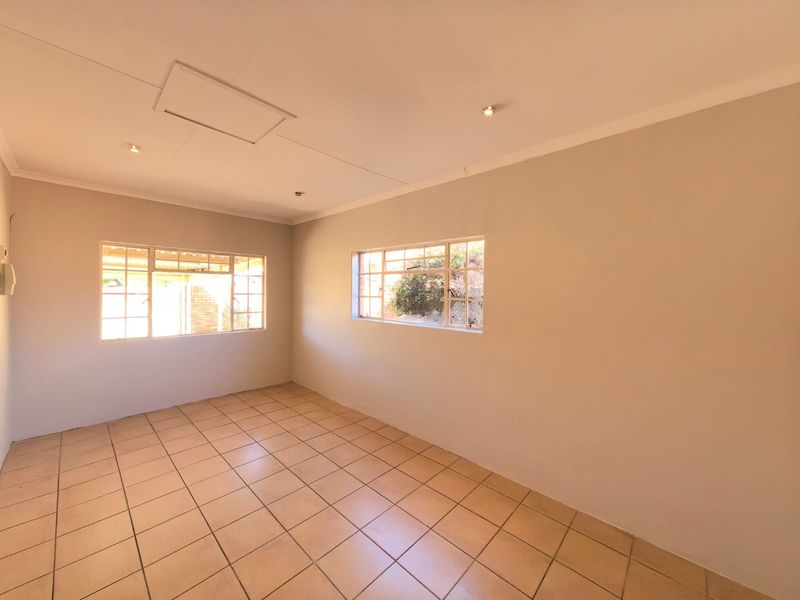 A bright, empty bedroom featuring neutral walls, tiled flooring, and steel-framed windows, offering a clean canvas for personalization.