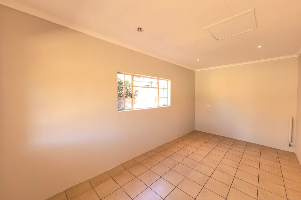 A bright, empty living area featuring neutral walls, tiled flooring, and a steel-framed window, providing a versatile blank canvas for interior design.