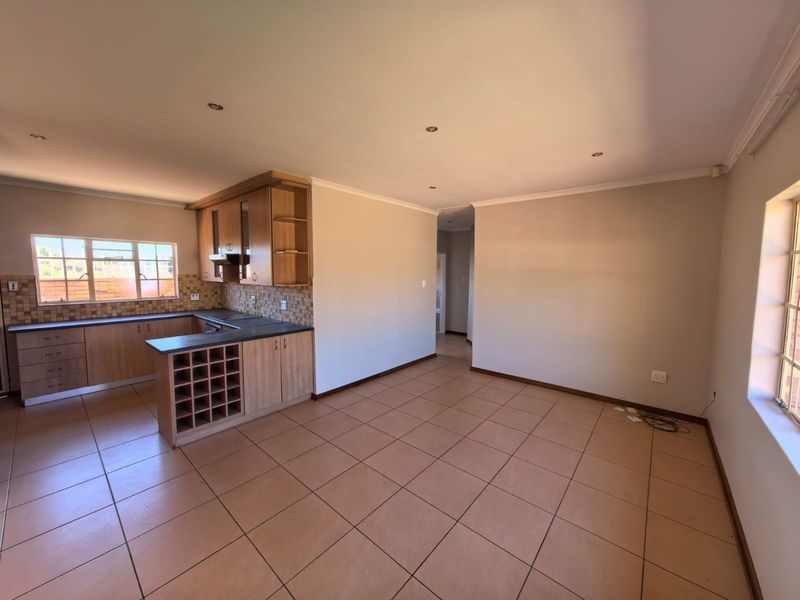 An open-plan kitchen and living area featuring tiled floors, built-in wooden cabinetry, a wine rack, and a mosaic tile backsplash.