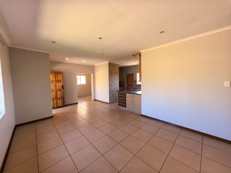 Spacious open-plan living area featuring neutral tiled flooring, recessed lighting, and a functional kitchen layout with built-in cabinetry and a breakfast island.