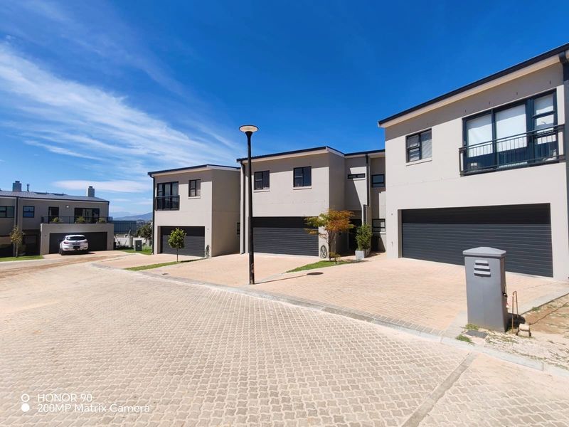 A modern residential complex featuring paved driveways, multiple sectional garage doors, and contemporary architectural design with clean exterior finishes.