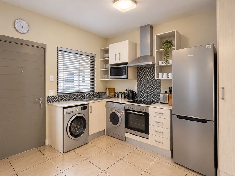 A well-maintained kitchen featuring built-in cabinetry, stainless steel appliances, a tiled splashback, and tiled flooring, offering a functional and clean workspace.