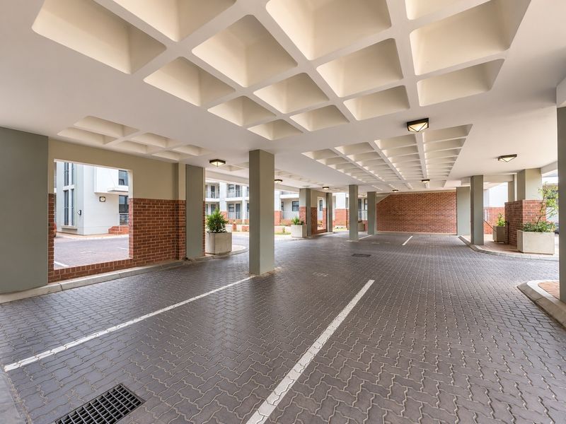A clean, well-maintained covered parking area featuring a distinctive coffered ceiling, brick accents, and durable paved flooring with designated parking bays.
