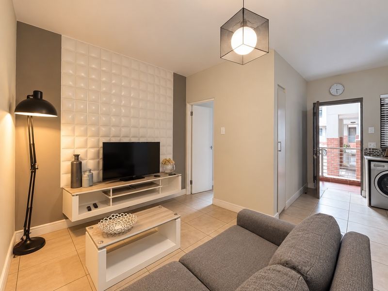 Modern open-plan living area featuring a textured feature wall, tiled flooring, and direct access to an outdoor balcony space.