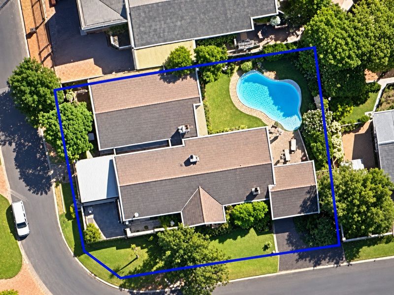 Aerial view of the property showcasing the house layout, tiled roof, swimming pool, landscaped garden, and paved driveway within the highlighted boundary.