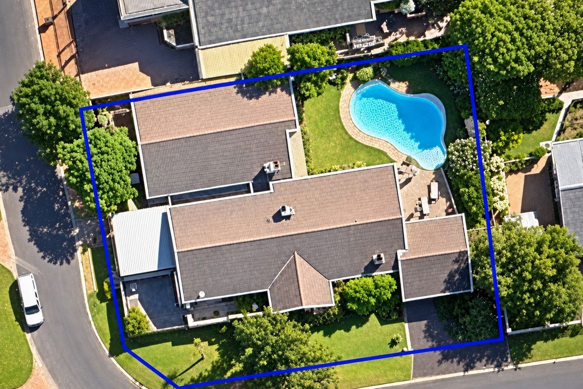 Aerial view of the property showcasing the house layout, tiled roof, swimming pool, landscaped garden, and paved driveway within the highlighted boundary.