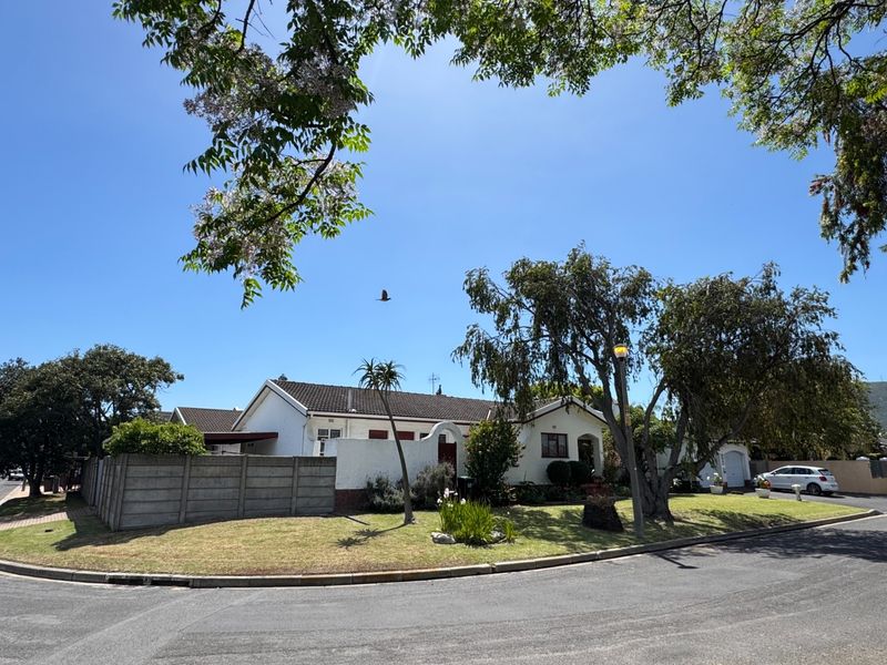 A well-maintained single-story residential property featuring a tiled roof, established garden, and a secure concrete boundary wall, viewed from the street.