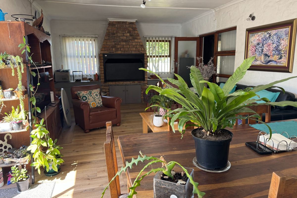 Spacious living room featuring a prominent brick fireplace, laminate flooring, and natural light through timber-framed windows.