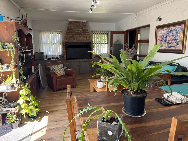 Spacious living room featuring a prominent brick fireplace, laminate flooring, and natural light through timber-framed windows.