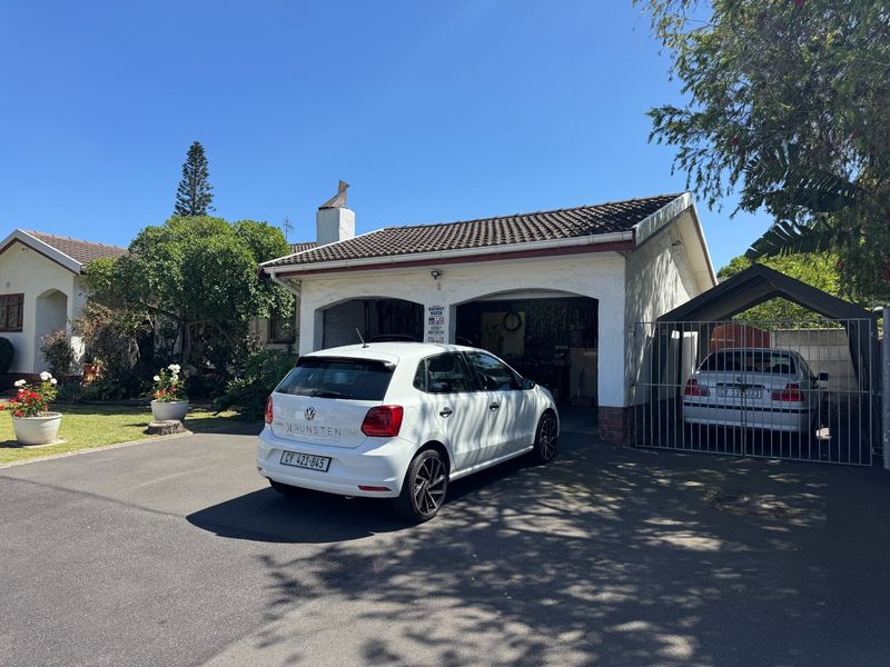 Front view of the property featuring a double garage, paved driveway, and a covered carport area.