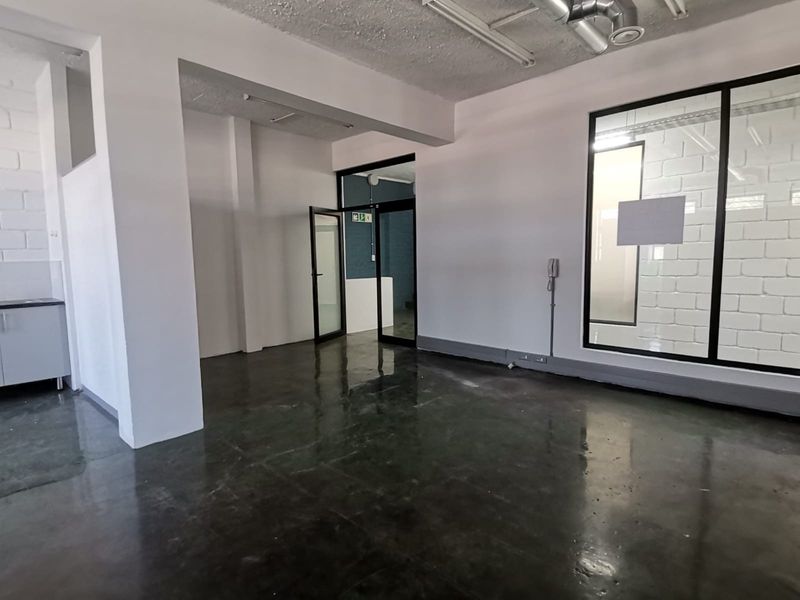 A modern, open-plan office space featuring polished concrete floors, exposed ceilings, and a glass partition wall, offering a clean and professional work environment.