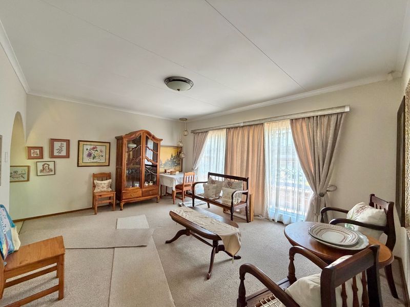 A spacious living room featuring neutral carpeting, coved cornicing, and a large sliding glass door that provides ample natural light.