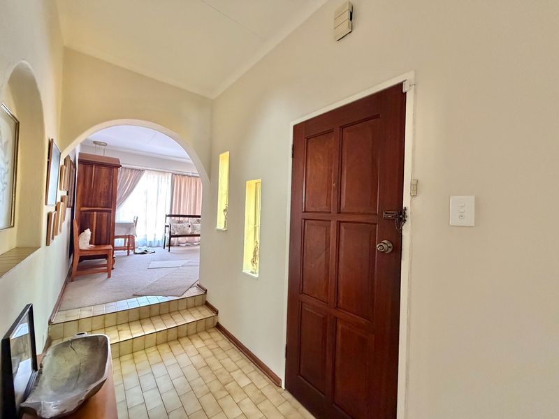 Entrance hall featuring tiled flooring, a timber panelled door, and an arched opening leading to the living area with recessed wall niches.