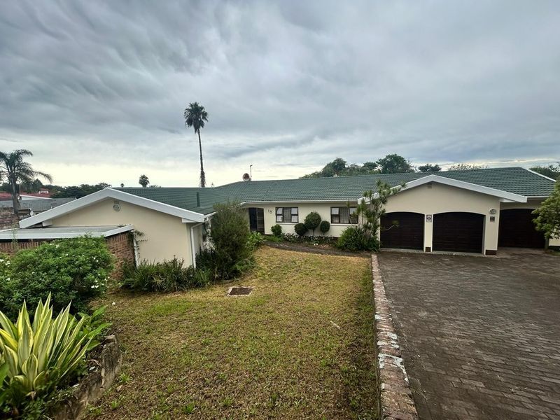 Front elevation of a single-story house featuring a double garage, paved driveway, and a tiled roof set on a landscaped residential lot.