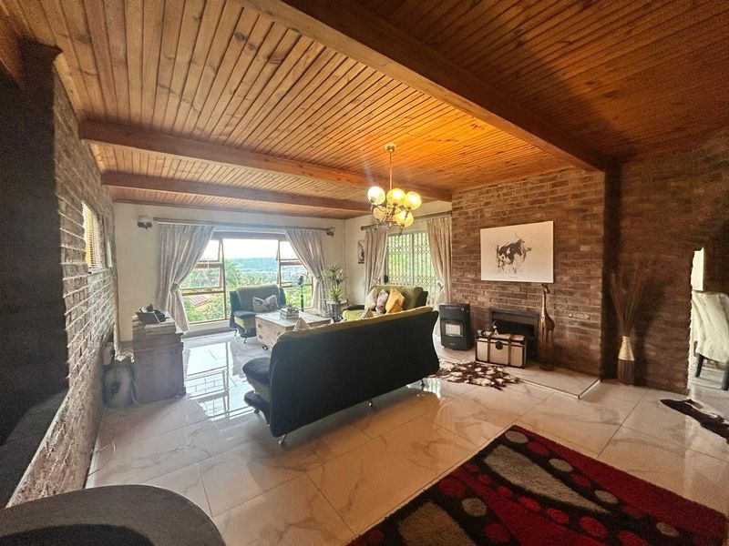 Spacious living room featuring a warm timber-clad ceiling, exposed brick walls, fireplace, and large sliding doors that provide ample natural light.